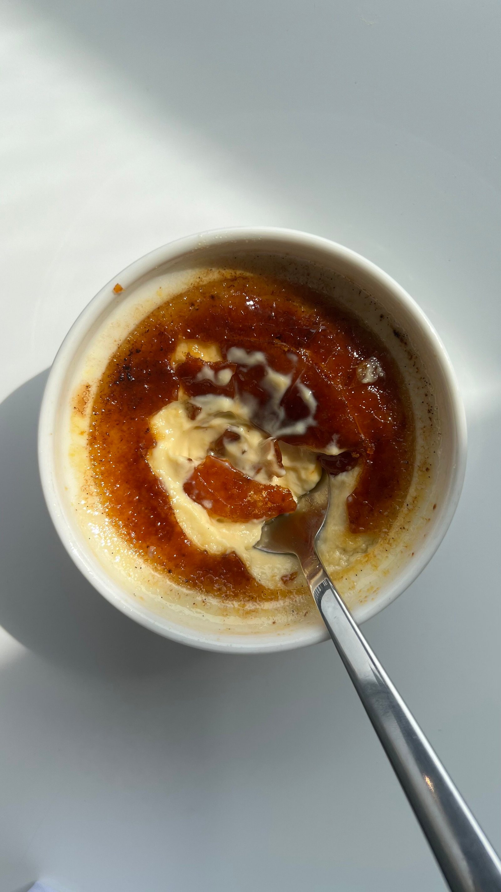 Spoon breaking through crème brûlée caramel topping